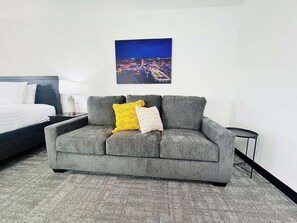 A comfortable sofa with vibrant throw pillows, situated next to a cozy bedroom for added relaxation space.