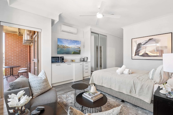 The studio features a queen bed, a mini kitchen, and a private bathroom with a shower.