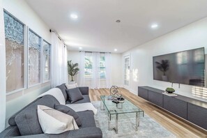 St Petersburg vacation rental living room with pull out sectional sofa, glass coffee table, smart TV and bright natural lighting 