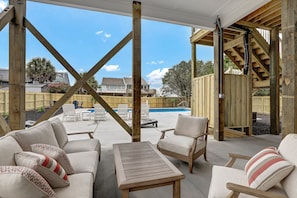 Covered outdoor space with ample seating and view of entire pool and yard.