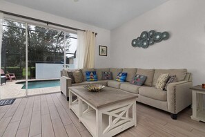 A spacious and comfortable living room with a pool view, cozy seating, and a modern design. Great for family time or quiet relaxation.