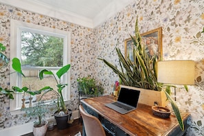 Charming home office with desk, abundance of natural light, & plants
