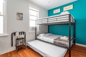 Bright Family Room: Sunny bedroom with Twin-over-Twin Bunk, pull-out Trundle, and full-size Crib—ideal for families. Includes a mini fridge, nightstand, wall-mounted TV, and a convenient luggage stand.