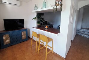 Living room with TV and bar connecting to Kitchen