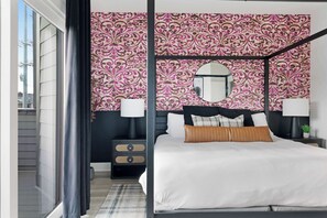 Cozy bedroom with a king bed, walk-in closet, and private balcony with two chairs. The en-suite bathroom features a modern shower for added comfort.