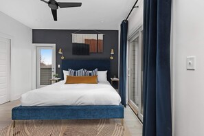 Elegant bedroom featuring a king bed, walk-in closet, and a private balcony with two chairs. The en-suite bathroom includes a modern shower for added comfort.