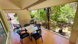 This spacious balcony surrounded by greenery is perfect for dining and relaxing.