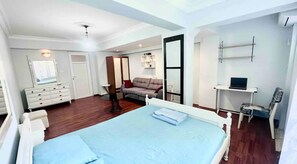 Living area with a projector, comfy sofa, air conditioning and a bed