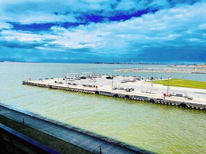 Expansive view of the harbor with serene blue waters, a docked pier, and Cedar Point in the distance. Perfect for relaxing while taking in the beauty of Lake Erie.