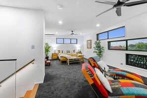 The master suite is beautifully accented with a vibrant lounging area that features an array of colorful chairs, designed for relaxation and entertainment in bright hues of orange and red, adding a playful yet stylish touch to the overall decor.