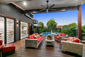 The patio area is a beautifully designed outdoor space that seamlessly connects to both the pool area and the lush garden, offering easy access to the best of the property's scenic surroundings. Decorated with comfortable, vibrant outdoor furniture.