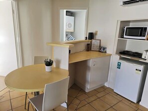 Compact kitchenette with a small dining area, equipped with essential appliances including a microwave and mini-fridge. The space is perfect for preparing light meals and enjoying a cozy dining experience in a relaxed setting.
