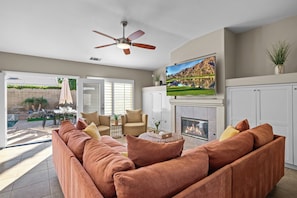 Living room offers comfortable seating, tons of natural light, a TV, and a fireplace.