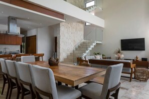 The ground floor is composed of the kitchen, dining area, and living room. Modern stairs lead to the second floor.
