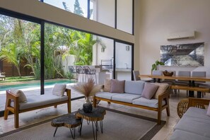 Modern and luxurious living-dining room. Stunning windows cover the ground and upper floors to connect with the outside.