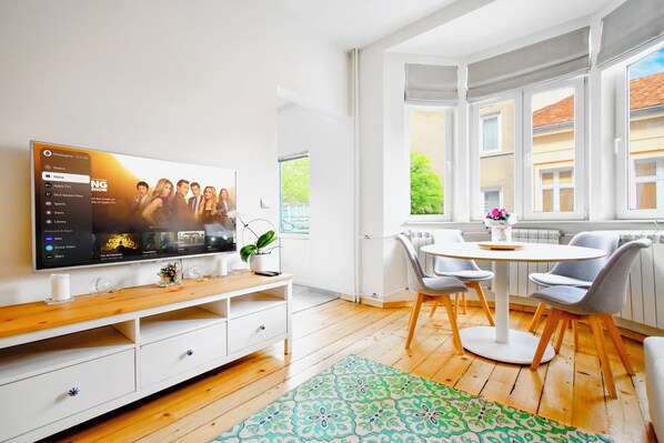 Relax in the bright and inviting living room, featuring stylish furniture, a smart TV, and a dining space perfect for enjoying meals together.