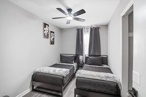 Perfect for restful nights with two twin beds, blackout curtains, calming gray tones, a Roku TV, and a closet stocked with games and storage options.