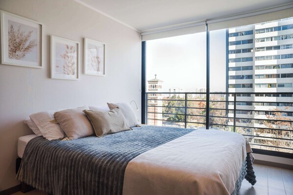 Relax in a cozy bedroom with stunning city views and natural light, perfect for a tranquil stay in the heart of the city.