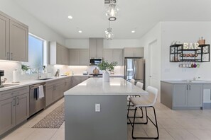 Sleek and spacious kitchen with a large island, stainless steel appliances, and elegant pendant lighting