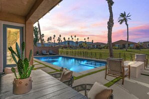 Luxurious poolside oasis with palm trees, glowing water, and a stunning sunset view.