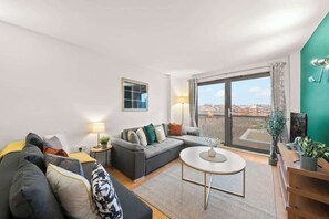 A perfect blend of sophistication and comfort, this living room features soaring ceilings, elegant lighting, and plush seating bathed in natural light. Rich textures, bespoke décor, and warm wood accents create an inviting space ideal for relaxation.