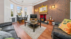 Bright and Inviting: A luxurious high-ceiling living area with thoughtful details like wall lighting, a coffee table, and a large mirror reflecting the room’s stunning design