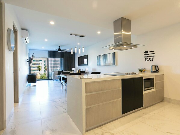 Enjoy the seamless flow of an open-concept living room designed for comfort and style. This inviting space features contemporary furnishings, a cozy sofa, and a large smart TV, perfect for relaxing or entertaining. The layout effortlessly connects the living area to the dining space and fully equipped kitchen, creating the ideal environment for gathering with family and friends...
