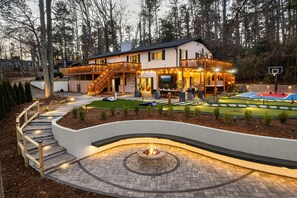 A lakefront retreat with outdoor amenities including a fire pit, mini golf, basketball court, and spacious decks perfect for relaxing and entertaining.
