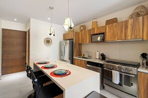 Fully equipped kitchen with coffee machine, cookware, and island seating.