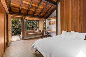 Wake up to nature in this serene bedroom retreat! Featuring warm wood accents, vaulted ceilings, and a cozy sitting nook that opens to tranquil outdoor views.
