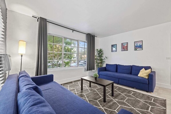 Bright and airy living room with comfy blue sofas and a large window offering plenty of natural light.