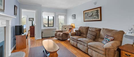 The spacious living room includes plenty of comfortable furniture, a TV, electric fireplace and access to the outdoor patio.