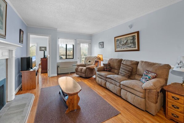The spacious living room includes plenty of comfortable furniture, a TV, electric fireplace and access to the outdoor patio.