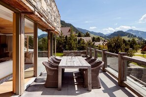 The spacious balcony features a large wooden table, perfect for enjoying a delightful breakfast with stunning mountain views.