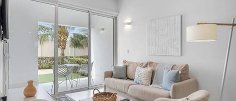 Bright living space filled with natural light, creating a cozy atmosphere for relaxation - Soft textures & stylish decor make this space inviting & comfortable for any moment - Glass doors open to a patio, bringing in fresh air & outdoor charm