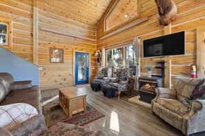 Gather around the cozy fireplace, perfect for chilly evenings, and enjoy the natural light streaming in through the large windows..