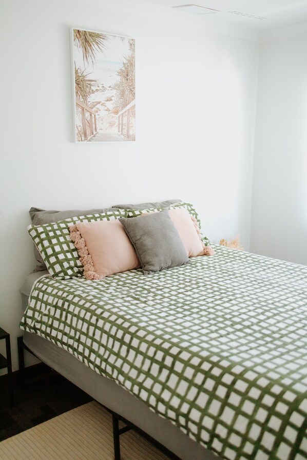 Relax and recharge in this stylish bedroom, adorned with a patterned bedspread, decorative pillows, and a touch of natural light.