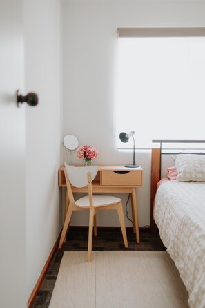 Unwind in this cozy bedroom featuring a comfortable bed, a charming desk area, and a touch of natural light.