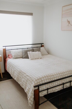 Unwind in this cozy bedroom, featuring a comfortable bed with a patterned bedspread and a warm, inviting atmosphere.
