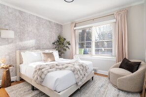 Queen bed in the bedroom with cozy ambience and reading chair