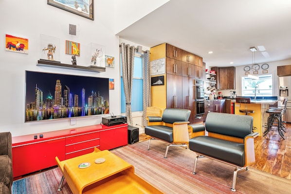 A modern living room with brown sofa, 60" 4K Smart TV and vibrant décor.
