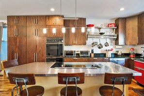 A sleek kitchen w/ wooden cabinets, stainless steel appliances & countertop.