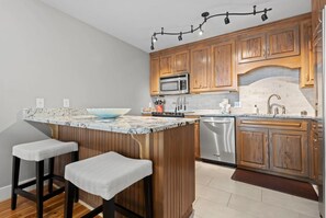 Prepare meals in the updated kitchen of our Cotton Bayou condo, featuring modern appliances, a stylish peninsula with extra seating, and a functional layout. Perfect for gathering and enjoying time with family and friends.