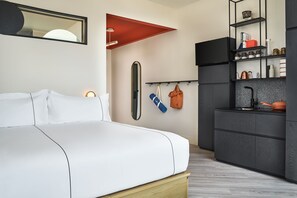 A beautifully curated guest room where modern design meets comfort, featuring sleek storage, warm accents, and a plush bed for a restful stay.