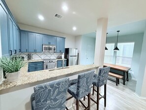 Gather in this inviting open-concept space featuring a modern kitchen with bar seating, a cozy dining area, and stylish blue accents. Perfect for cooking, dining, and sharing moments with loved ones. Your ideal Houston getaway starts here!