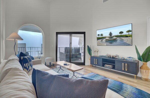 Cozy living room with a sectional sofa, wide-screen TV, and balcony access.