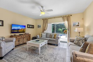 The open living area of this home seamlessly connects to the outdoor spaces, offering a stunning view of the spa, heated pool, and BBQ dining area.