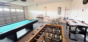 Games room at the front of the house featuring a pool table, air hockey, table football, and seating area.