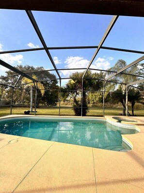 An outdoor heated pool and hot spa overlooking a lush green yard offers a perfect blend of luxury, comfort, and tranquility, creating an ideal space for relaxation.