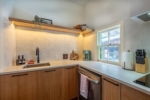 "Fully equipped kitchen with modern cabinetry, sleek countertops, and all essentials for preparing meals (stovetop included, no oven).